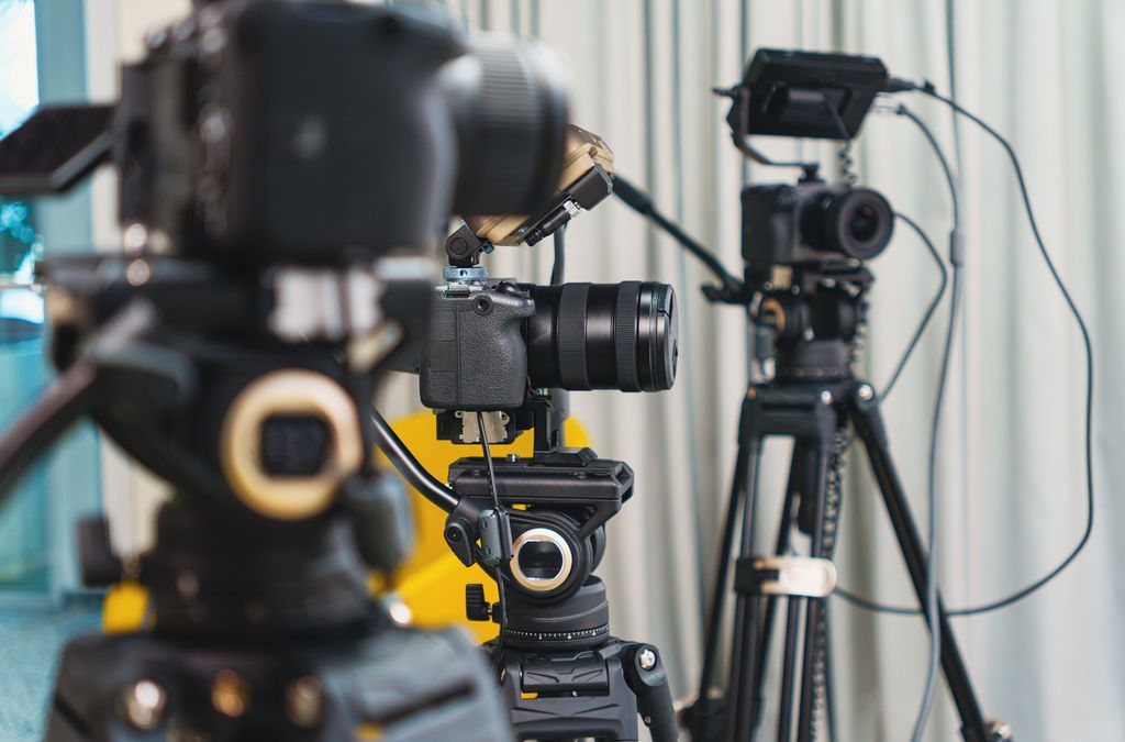 Close-up of high-end video cameras and tripods in a modern studio setting.